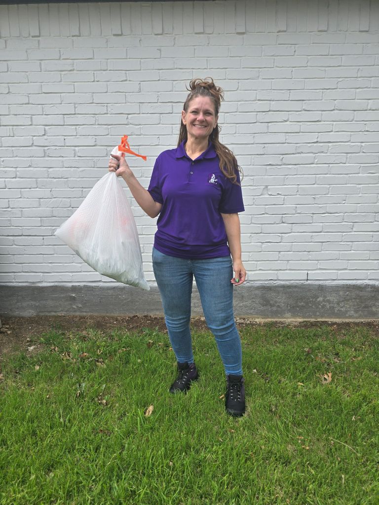 Woman holding trash bag outdoors.